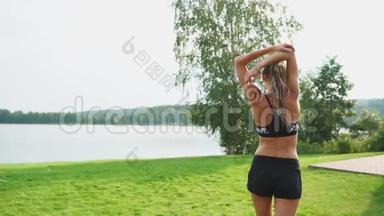 一位身材苗条、穿着运动服的美女正准备在她附近的草坪上开始训练